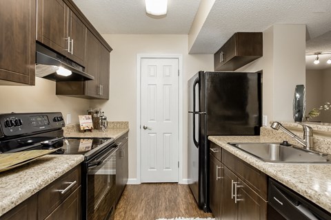 redesigned kitchen with granite counter tops and stainless steel appliances and a black refrigerator
