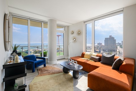 a living room with orange couches and a view of the city and the ocean