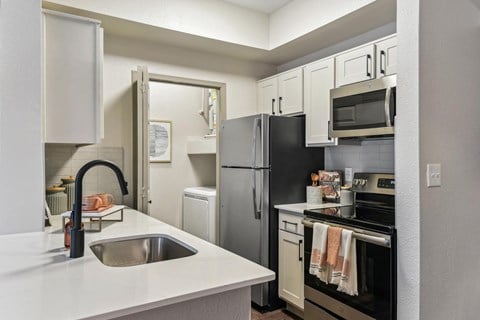 A kitchen with a black refrigerator and white countertops.at Onyx183, Austin, TX  