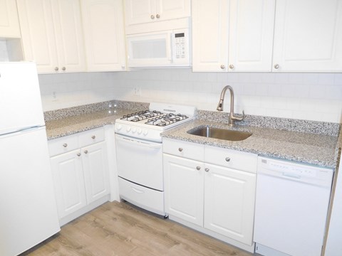 a kitchen with white cabinets and granite counter tops and white appliances