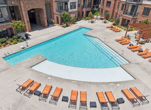 A swimming pool surrounded by orange lounge chairs.
