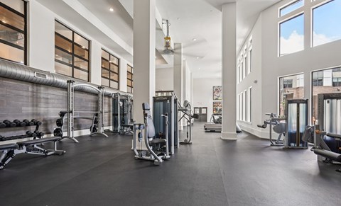 A spacious gym with a variety of equipment and a large mirrors on the wall.
