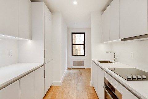 a white kitchen with white cabinets and a window