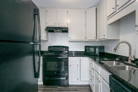 a kitchen with black appliances and white cabinets