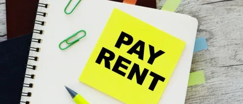 A neon post-it on a notebook with the "pay rent" message written on it to illustrate a late rent notice.