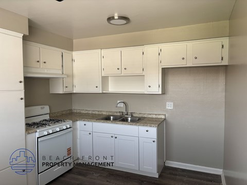 A kitchen with white cabinets and a stove top oven.