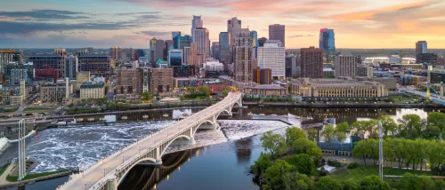 View of Minneapolis, MN city skyline over the river at dusk.