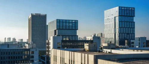A view of the skyline in a city, with modern office buildings visible along the horizon, beneath a bright blue sky.