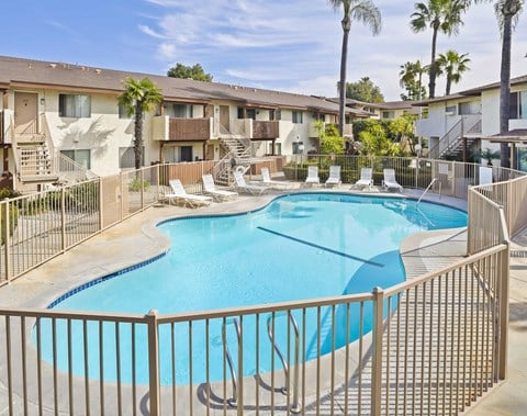 A pool surrounded by a fence and chairs.