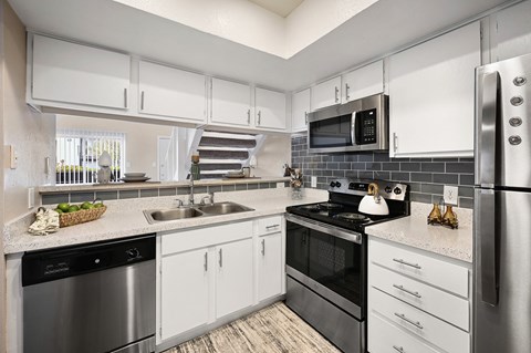 a kitchen with white cabinets and stainless steel appliances